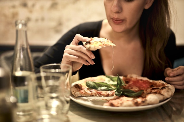 picture of woman eating neapolitan pizza